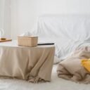 A cozy, minimalist living room featuring neutral tones, soft furnishings, and a covered couch.